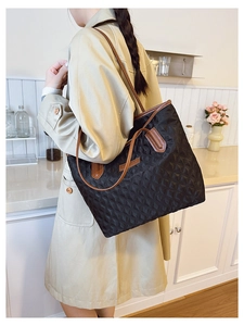 Close-up of quilted black tote bag showing durable texture and brown contrast straps