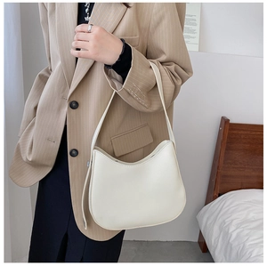 Gros plan d'un sac hobo blanc minimaliste porté avec un blazer beige à rayures élégant