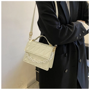 Detailed view of cream quilted crossbody bag with acrylic chain and gold metal hardware