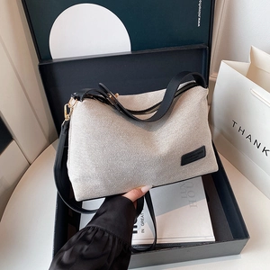 Borsa hobo minimalista in tela beige con spalline in pelle nera ed etichetta moda