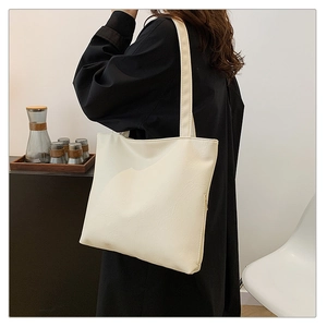 Close-up of minimalist cream tote bag with fine leather texture and shoulder strap detail