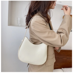 Sac sous le bras chic blanc crème en forme de croissant porté par un mannequin en blazer