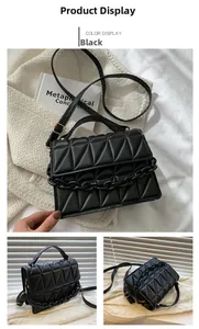 Detail of black quilted shoulder bag featuring gold hardware and thick chain strap