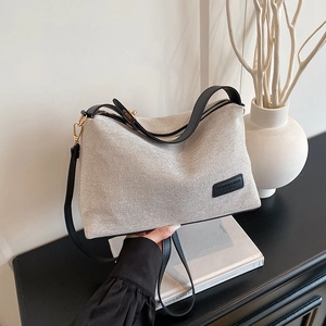 Borsa tote minimalista in tela con finiture in pelle nera mostrata in un ambiente lifestyle