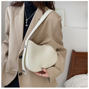Détail d'un sac hobo demi-lune beige avec large bandoulière porté par un mannequin