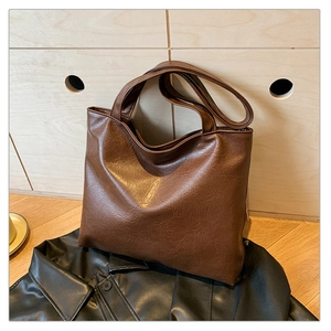 Close-up of vintage brown PU leather tote bag with soft wrinkled texture on leather jacket