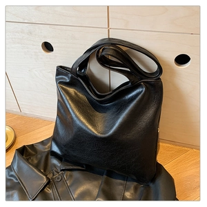 Detail of black tote bag featuring retro wrinkled texture and smooth metal zipper