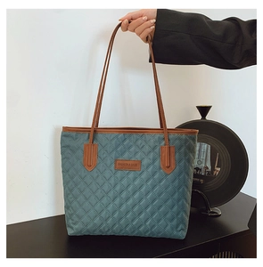 Close-up of quilted tote bag with brown leather straps and blue water-resistant fabric