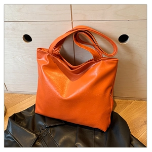 Detail of orange tote bag with lychee texture on leather surface and metal zipper