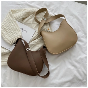 Sacs portés épaule demi-lune minimalistes en cuir café et beige sur un tissu texturé