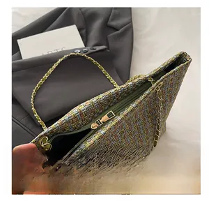 Close-up of olive and grey tweed fabric texture with gold zipper and chain strap