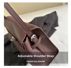 Detail of adjustable shoulder strap with silver buckle on dark brown leather handbag