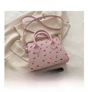 Close-up of pink cherry print handbag featuring double ring handles and shoulder strap