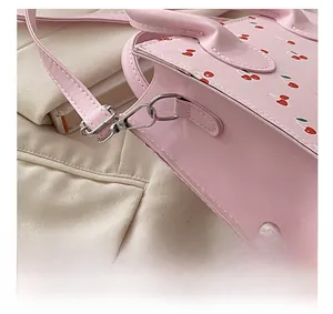 Detail of silver metal hardware and detachable strap on pink cherry pattern bag