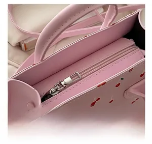 Detail of metal silver zipper closure on pink cherry pattern PU leather handbag