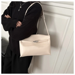 Detail of minimalist cream leather underarm bag featuring silver twist-lock and buckle strap