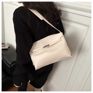Detail of minimalist beige leather shoulder bag with silver turn-lock and adjustable strap