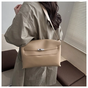 Side view of beige minimalist underarm bag with silver turn-lock clasp on a model