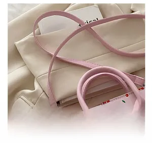 Detail showing the adjustable shoulder strap and cherry print on the pink handbag