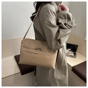Detail of minimalist beige leather shoulder bag featuring a silver twist lock and strap