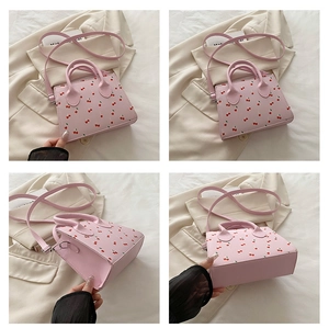 Detail view of pink cherry print crossbody bag with handles and adjustable shoulder strap