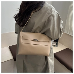 Minimalist beige shoulder bag with silver clasp shown on model in a modern interior setting