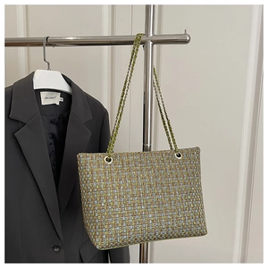 Detail van meerkleurig geweven patroon en gouden ketting op een luxe kleine handtas