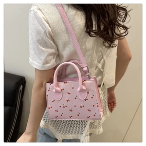 Detailopname van roze crossbodytas met kersenprint, zilveren hardware en bovenhandvat