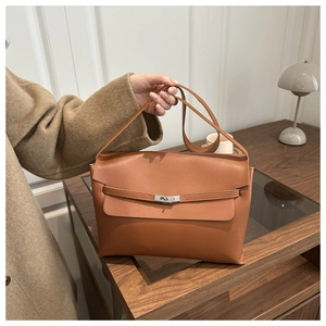 Detailed view of brown leather bag with classic metal swivel lock and strap decoration