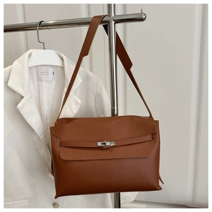 Close-up of caramel brown shoulder bag with signature strap buckle and flap detail