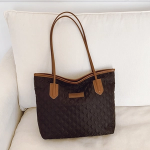 Quilted black tote bag with brown leather handles and spacious interior for daily commute