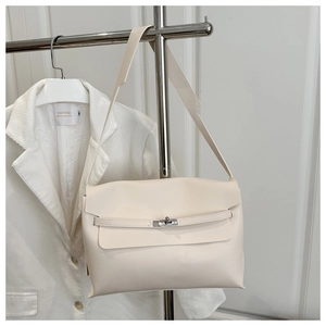 Macro view of ivory faux leather shoulder bag with silver turn-lock and flap detail