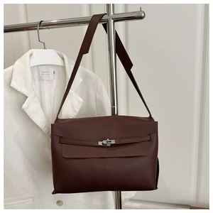 Detail of dark brown leather crossbody bag with silver rotating lock on a metal stand