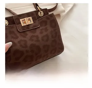 Détail d'un sac à main léopard avec fermoir rotatif doré et texture en daim de qualité