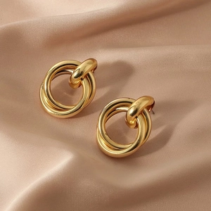 Luxurious gold interlocking circle stud earrings on champagne satin background