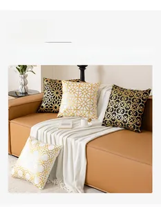 Luxe geometric gold foil cushion covers on a brown leather sofa with a white blanket