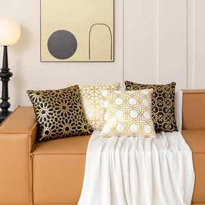 Set of four geometric gold foil pillow covers in black and white on a leather sofa