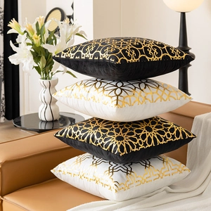 Set of four black and white geometric gold stamped velvet pillow covers on a leather sofa