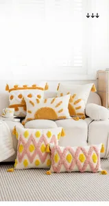 Detail of tufted embroidered pillow with sun motif and yellow corner tassels