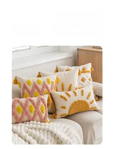 Detailed close-up of tufted geometric patterns and tassels on cream and yellow pillows