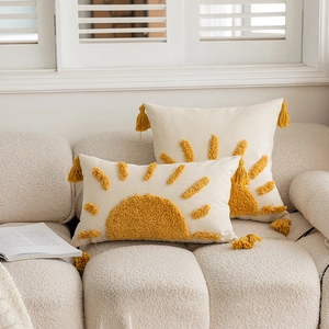 Bohemian tufted cushion covers with sun patterns and yellow tassels on a beige sofa