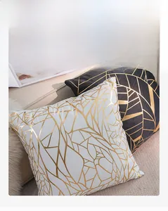 Detail of two gold geometric leaf pattern velvet pillow covers in black and white colors