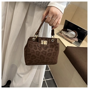 Détail d'un sac à main léopard avec fermoir rotatif doré dans un cadre lifestyle chic