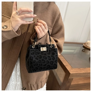 Détail d'un sac à main léopard avec boucle dorée et texture givrée tenu par un modèle