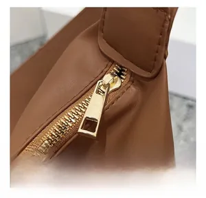 Detail of smooth gold-tone zipper and fine stitching on a brown tote handbag