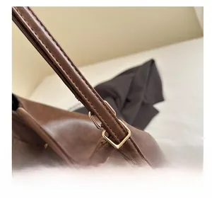 Detail of adjustable golden metal buckle on dark brown leather shoulder bag strap