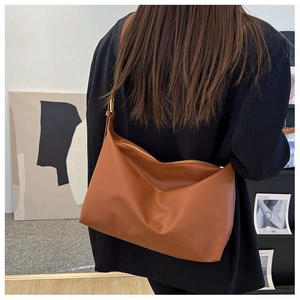Brown leather tote bag shown from a side back view on a model for a modern commute style
