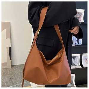 Detail of caramel hobo bag with adjustable gold buckle and soft leather texture