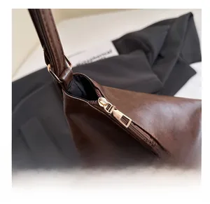 Detail of smooth metal zipper and glossy dark brown leather texture on a tote bag