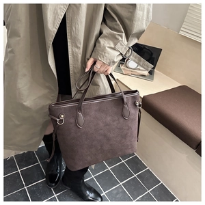 Vue de dessus d'un grand sac cabas en daim marron foncé porté dans un bureau élégant